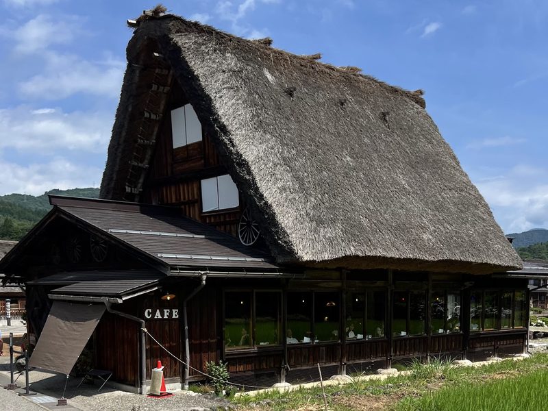 急勾配の茅葺き屋根がそびえる、文化喫茶 郷愁の合掌造りの建物